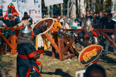 Bir grup savaşçının önünde poz veren iki dişi Viking..