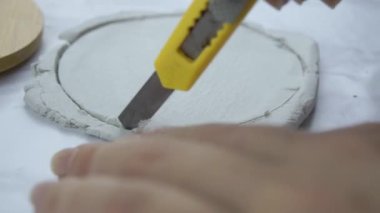 Kadınların elleri kırtasiye bıçağıyla çamurdan çember oluşturuyor.. 