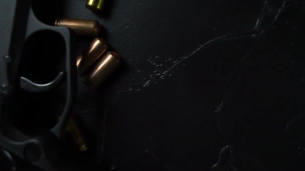 Armes à feu et munitions reposent sur une table texturée noire. — Video