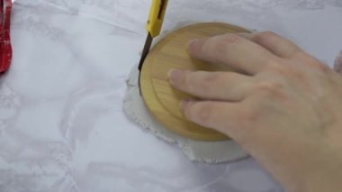 Adam kırtasiye bıçağıyla çamurdan çember kesiyor..