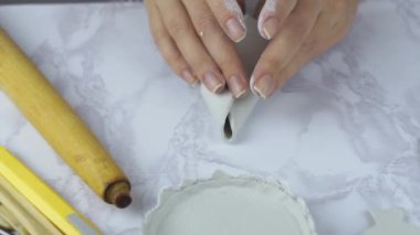 İnsan elleri beyaz çamurdan minyatür kulübe yapar.. 