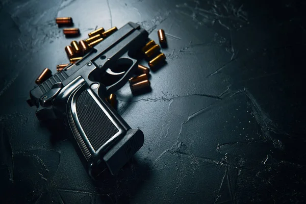 Pistola com cartuchos na mesa de concreto escuro. — Fotografia de Stock