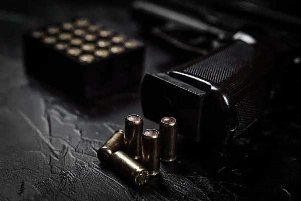 Pistola com cartuchos na mesa de concreto preto. — Fotografia de Stock