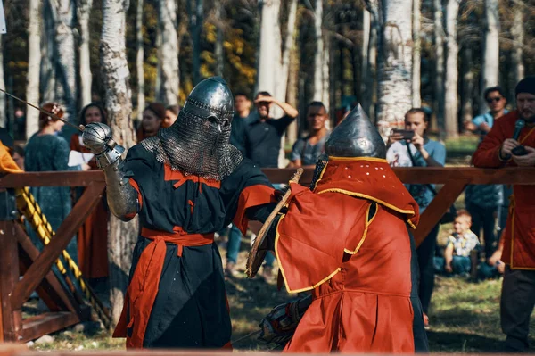 Two knights fight with swords in front of an audience. — Stock Photo, Image