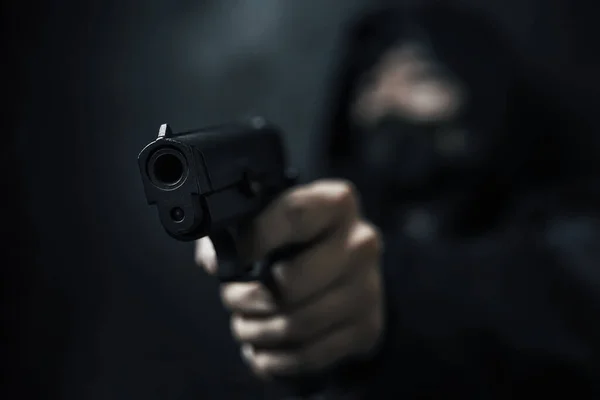 Kapüşonlu ve maskeli bir adam silahla tehdit ediyor..