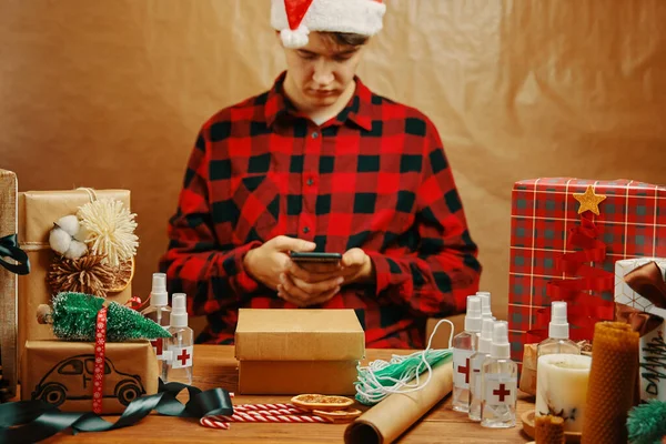 Uomo in camicia a quadri con cellulare in decorazioni natalizie. — Foto Stock