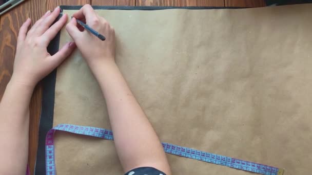 Frauenhände schreiben Zahlen und zeichnen Skizze mit Bleistift auf Kraftpapier. — Stockvideo