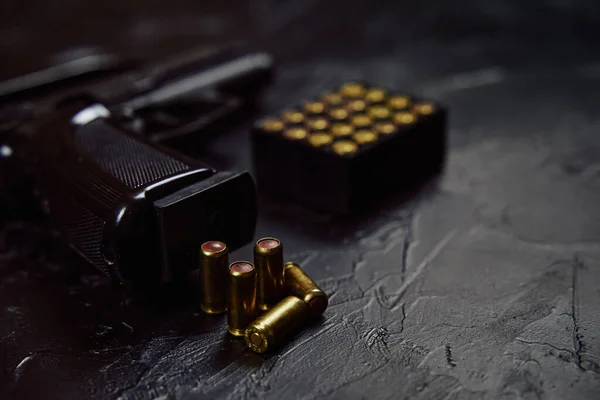 Pistola con cartuchos sobre mesa de hormigón negro. — Foto de Stock