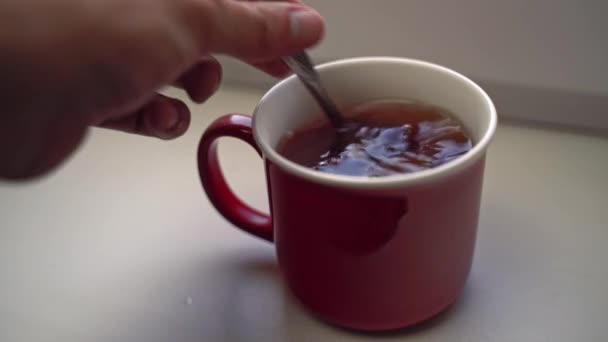 Mensen hand giet lepel suiker in keramische mok met thee. — Stockvideo