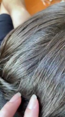 Kadın elleri erkeğin kafasındaki kahverengi saçlara dokunur..