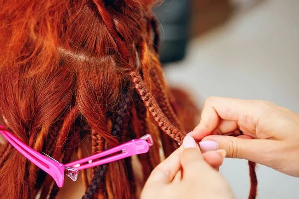 Hairdressers hands braid girls ginger dreadlocks. — Stock Photo, Image