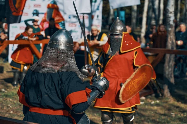 Caballeros luchan con espadas y escudos frente al público. — Foto de Stock