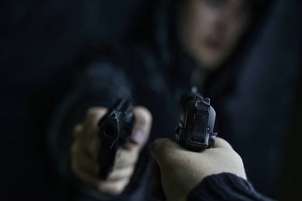 Första person syn på handen med pistol riktad mot kille med revolver. — Stockfoto