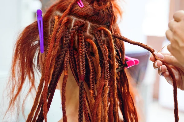 Hairdressers hands braid girls ginger dreadlocks. — Stock Photo, Image