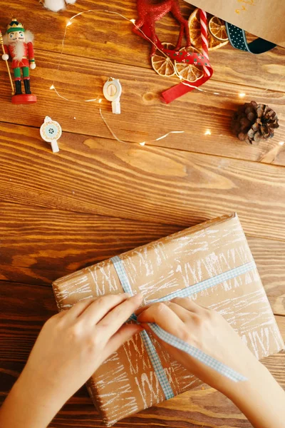 Frauenhände binden Schleife an Weihnachtsgeschenk. — Stockfoto