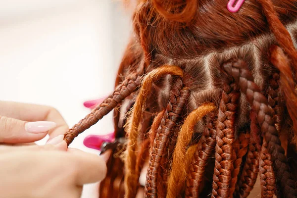 Hairdressers hands braid girls ginger dreadlocks. — Stock Photo, Image