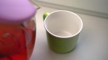 İnsan, Seylan çaydanlığından yeşil seramik kupaya çay döker.