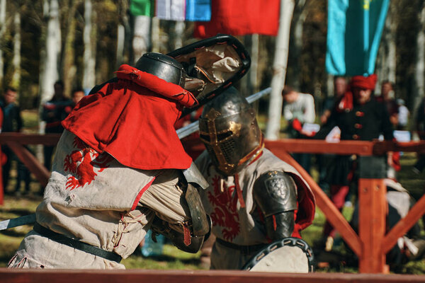Two knights in armor imitate a sword fight.