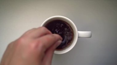 Erkekler çay eşliğinde beyaz seramik bardağa bir kaşık dolusu şeker döker..