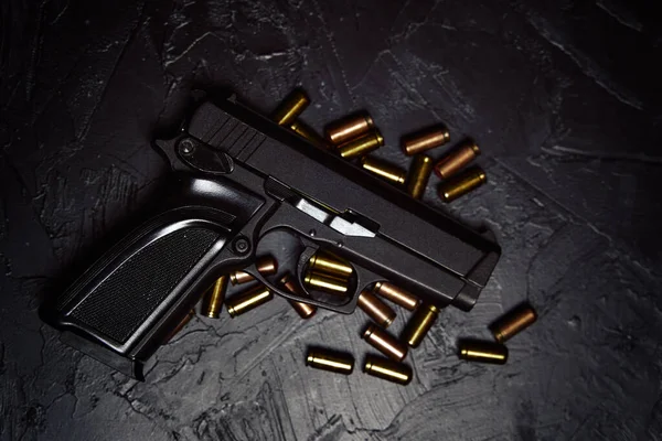 Pistola com cartuchos na mesa de concreto preto. — Fotografia de Stock
