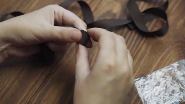 Womens hands twist brown ribbon into roll. — Αρχείο Βίντεο