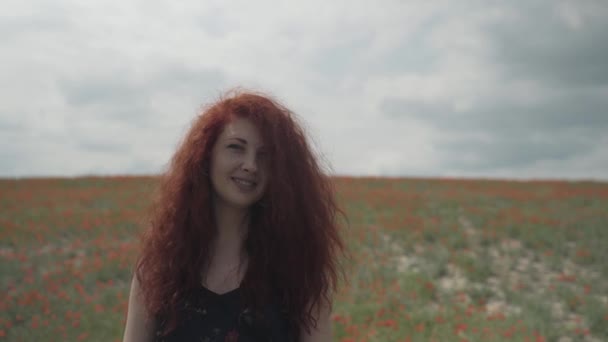 Schöne Frau mit Sommersprossen auf dem Hintergrund des Mohnfeldes. — Stockvideo