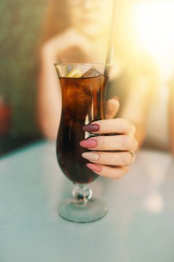 Pembe ve mor manikür bardaklı kadın eli kokteylli..