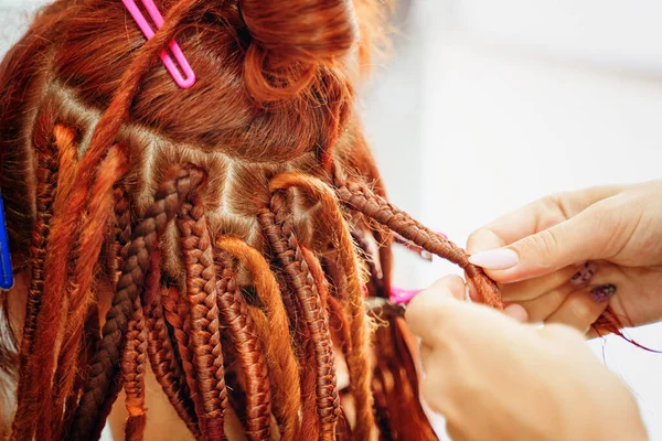 Hairdressers hands braid girls ginger dreadlocks. — Stock Photo, Image