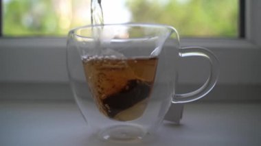 Adam cam bardakta çay poşeti hazırlıyor..