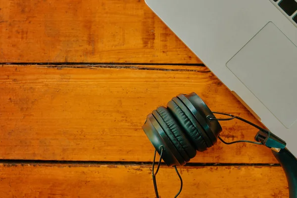 Laptop ve kablosuz kulaklıklar ahşap masada..