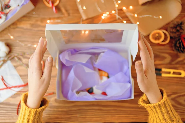 Menschen Hände in Strickpullover öffnen Geschenkbox mit Weihnachtsplätzchen. — Stockfoto