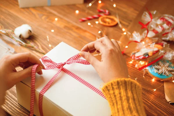 Mädchen Hände binden rote Schleife Schleife auf weißem Geschenkkarton. — Stockfoto