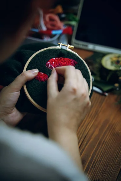 Girl is embroidering mushroom cap on green cloth. — Stock Photo, Image