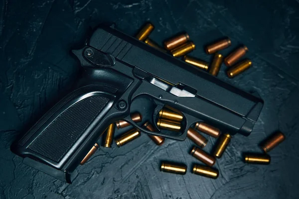 Pistola com cartuchos na mesa de concreto escuro. — Fotografia de Stock