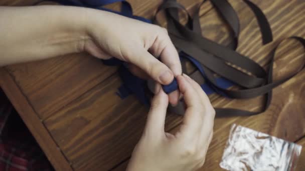 Womens hands twist blue ribbon into roll. — Stock Video