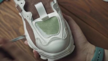 Kadınların elleri kapalı beyaz spor ayakkabılara yeşil akrilik boya sürerler..