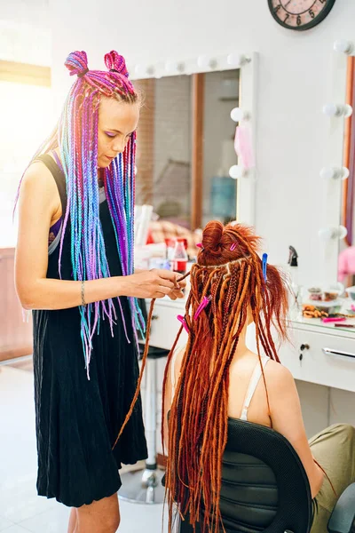 Femme coiffeur tisse pour fille gingembre dreadlocks. — Photo