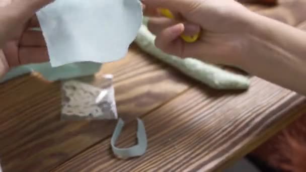 Mulher corta detalhes de roupas para boneca de pano com tesoura de costura. — Vídeo de Stock