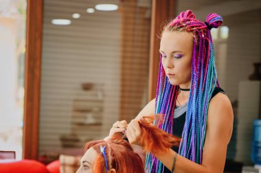 Renkli örgü örgülü kadın berber. Zencefilli örgü örüyor..