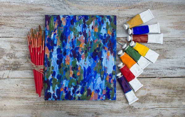 Paints, brushes, palette, canvas and painted. — Stock Photo, Image