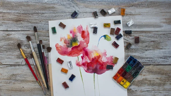 Watercolor paint, brush, painted flowers.