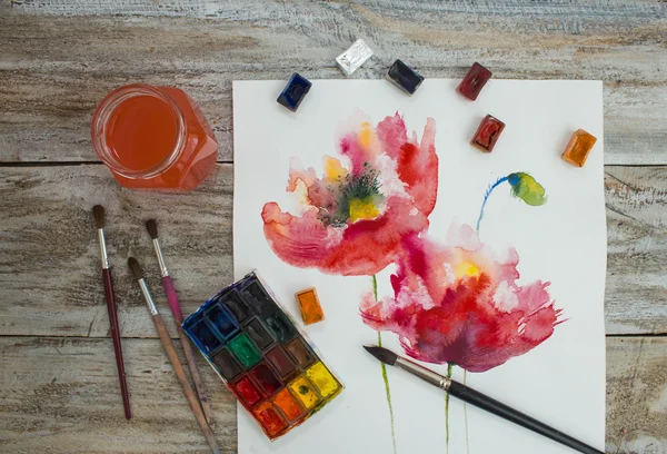 Watercolor paints, brushes and painted flowers on wooden background. — Stock Photo, Image