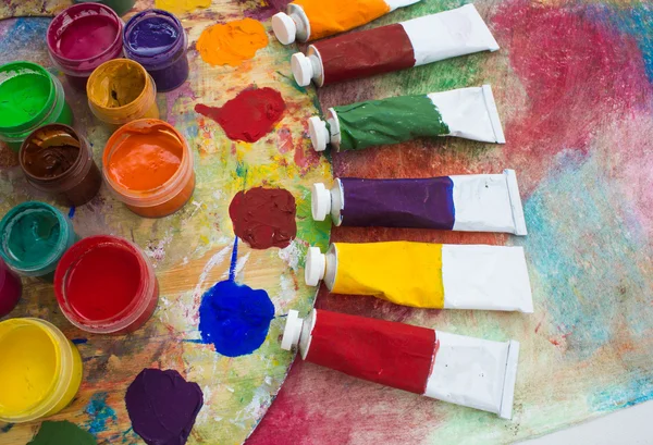 Pinturas, pinceles y paleta sobre el fondo colorido . — Foto de Stock