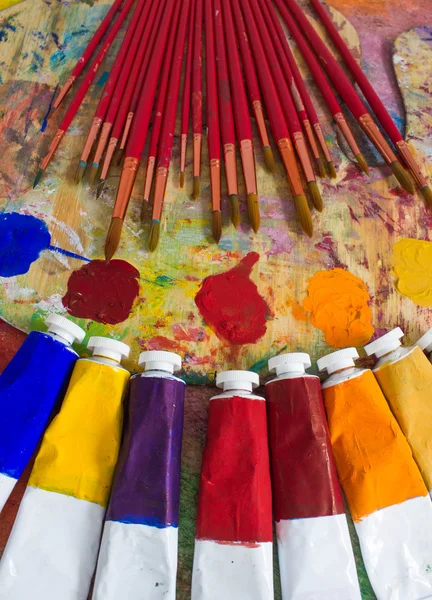 Pinturas, pinceles y paleta sobre el fondo colorido . — Foto de Stock