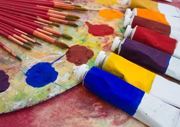 Paints, brushes and palette on the colorful background. Stock Image