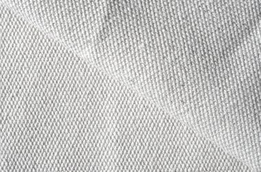 Beyaz tekstil kumaşına yakın çekim, ince dokuma ve yumuşak dokuyu ortaya çıkarıyor.