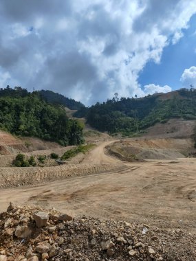 Bereketli tropikal yağmur ormanları ve büyük ormansız, kazılmış tepeler arasında, madencilik için çıplak toprak ya da dramatik, bulutlu bir gökyüzü altında inşaat için.