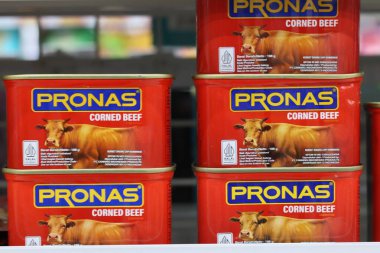 24 Ekim 2025 Balikpapan-Endonezya PRONAS markalı konserve sığır konservesinin üst üste dizilmiş perakende sergilenmesi, bir süpermarket ortamında inek resimli belirgin kırmızı ve sarı etiketleri göstermektedir..