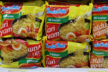 24 Ekim 2025 Balikpapan-Endonezya Indomie Instant Noodles 'ın sıkıca istiflenmiş sarı paketleri arasında popüler 
