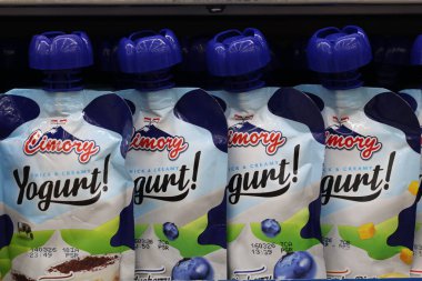 24 Ekim 2025 Balikpapan-Endonezya. Koyu renkli bir süpermarket rafında özgün mavi çiçek şekilli kapsüllü bir sıra Cimory marka ve kremalı yoğurt kesesi..